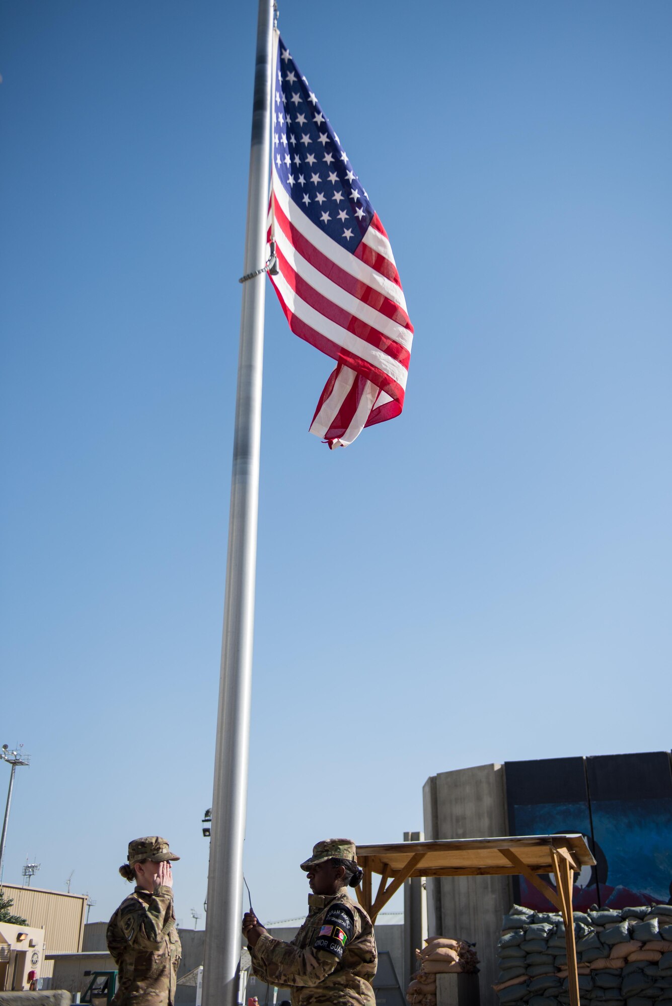 U.S. Air Force Staff Sgt. Anna Melhado and Senior Airman Chelsea Shields both members of the Bagram Air Field Honor Guard lower the flag during a Memorial Day retreat ceremony at Bagram Air Field, Afghanistan, May 25, 2015. Memorial Day is dedicated to remembering U.S. men and women who gave their lives while in military service protecting and defending national interests. (U.S. Air Force photo by Tech. Sgt. Joseph Swafford/Released)