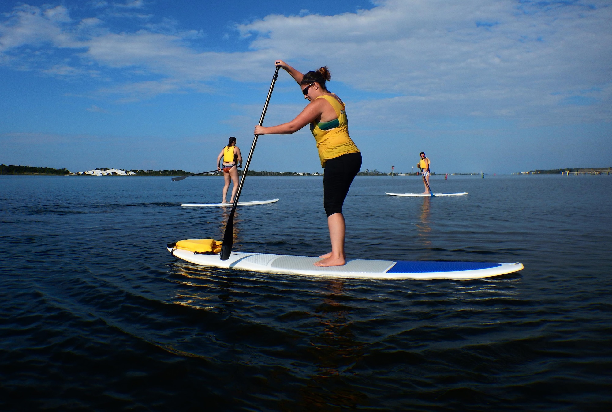 Sara Francis, Kirsten J. Nunweiler and Stephany Pippin, assigned to the 1st Special Operations Force Support Squadron, paddle in the Santa Rosa Sound during a stand up paddle boarding class at Hurlburt Field, Fla., June 4, 2015. The Outdoor Recreation SUP class is new to Hurlburt Field this year and classes are held Tuesdays and Thursdays from 7:30 a.m. to 8:30 a.m. weekly at the Sound Side. (U.S. Air Force photo/Airman Kai White)