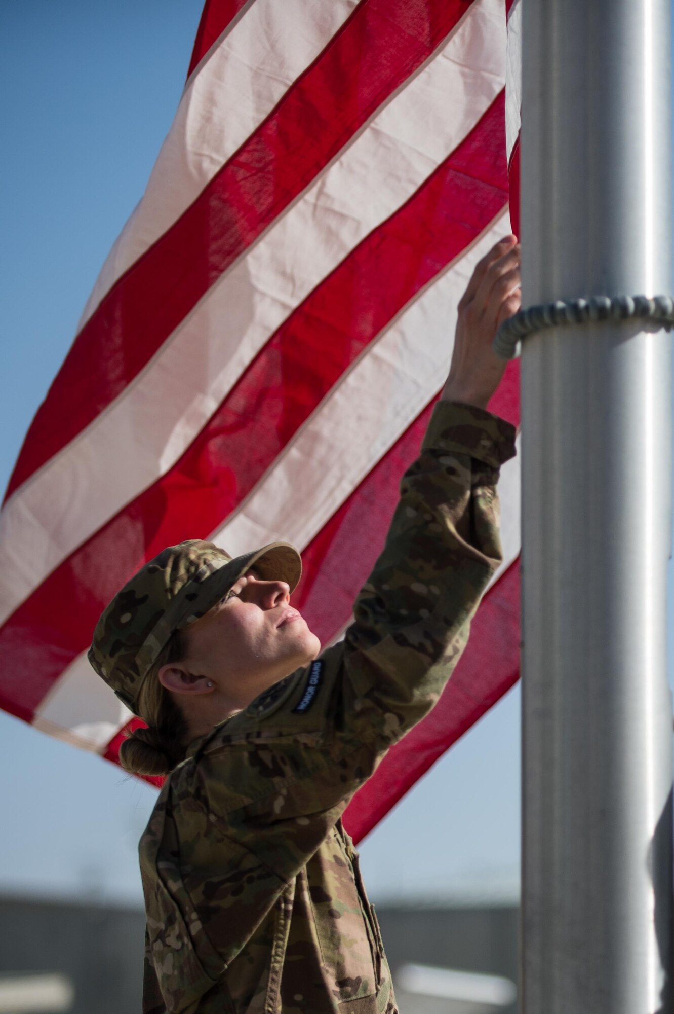 U.S. Air Force Senior Airman Chelsea Shields, Bagram Air Field honor guard member, helps lower the flag during a Memorial Day retreat ceremony at Bagram Air Field, Afghanistan, May 25, 2015. Memorial Day is dedicated to remembering U.S. men and women who gave their lives while in military service protecting and defending national interests. (U.S. Air Force photo by Tech. Sgt. Joseph Swafford/Released)