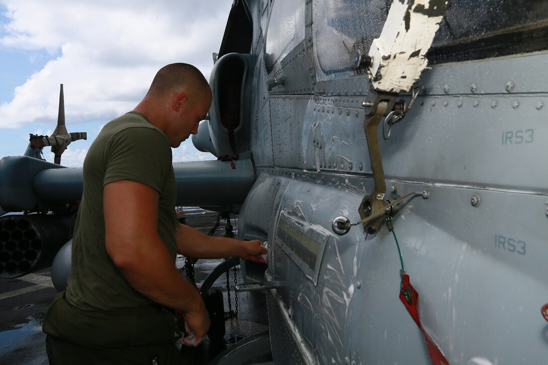 U.S. Marine Lance Cpl. Robert Sandlin cleans an AH-1Z Viper aboard the USS Anchorage (LPD 23) in the Philippine Sea, June 6, 2015. Sandlin is a Ground Support Equipment Mechanic with Marine Medium Tiltrotor Squadron 161 (Reinforced). The Marines of VMM-161 (Rein) clean and maintain the helicopters aboard the Anchorage regularly to ensure they are kept in the highest state of readiness. (U.S. Marine Corps photo by Sgt. Jamean Berry/ Released)