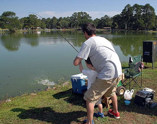 A father helps his son reel in a catfish during Marine Corps Logistics Base Albany’s 27th annual Buddy Fishing Tournament at Covella Pond here, June 6.