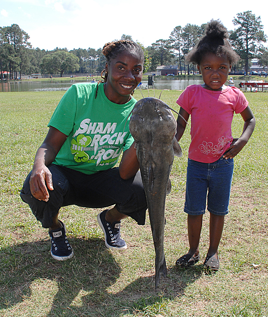 A mother holds the largest catch of the day, a 12.2-pound catfish, for her daughter during Marine Corps Logistics Base Albany’s 27th annual Buddy Fishing Tournament at Covella Pond here, June 6.