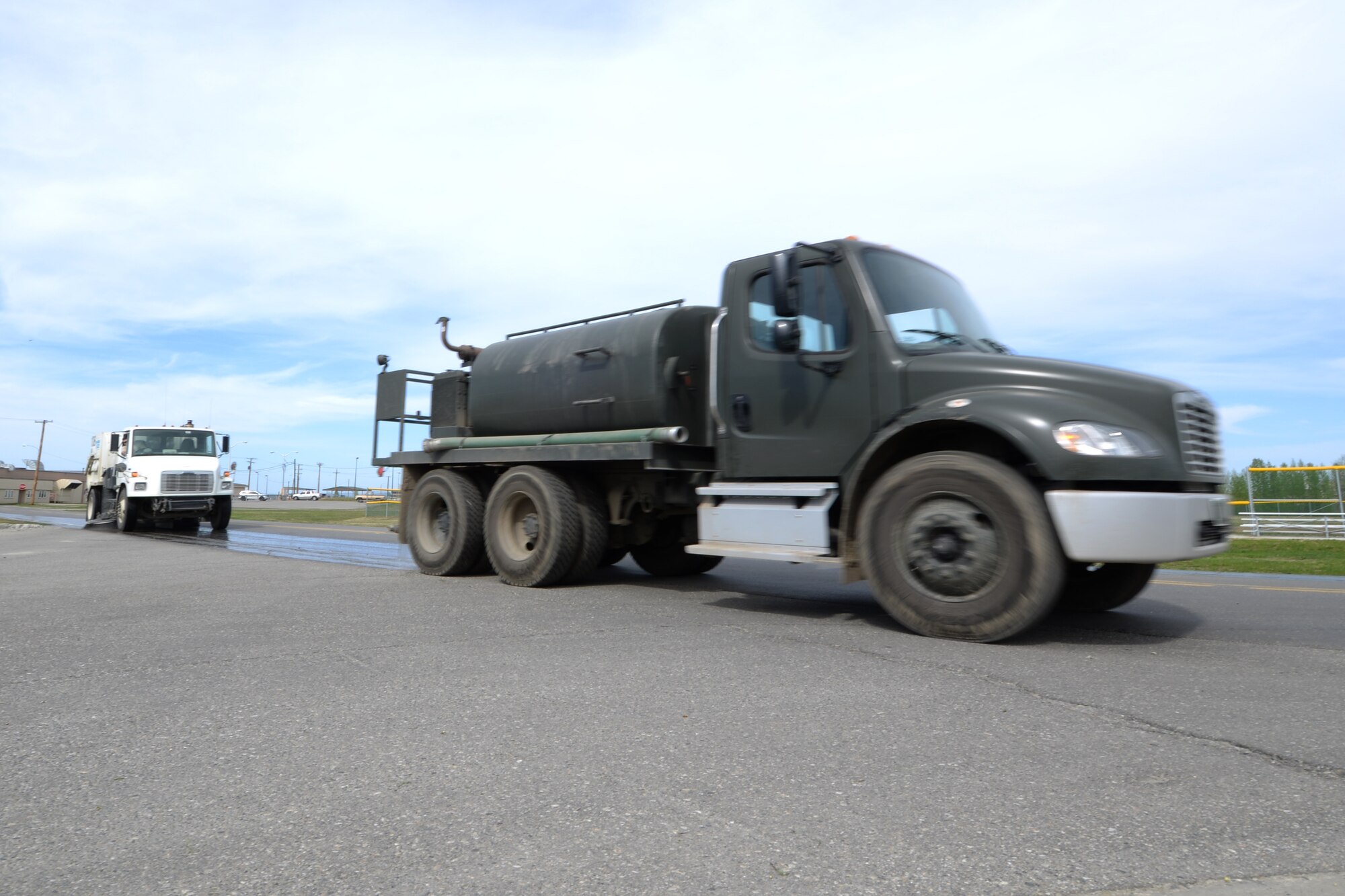 U.S. Air Force Dirt Boyz assigned to the 354th Civil Engineer Squadron clean the streets around Eielson Air Force Base, Alaska, using a water truck and street sweeper May 15, 2015. Putting water down prior to being swept ensures dust is kept to a minimum. (U.S. Air Force photo by Senior Airman Ashley Nicole Taylor/Released)