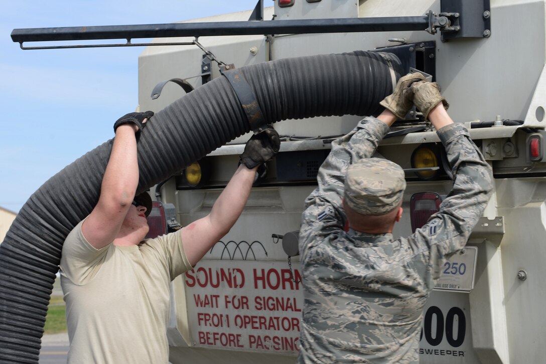 U.S. Air Force Airmen 1st Class Adam Pryor and Andrew Sundling, both 354th Civil Engineer Squadron pavements and heavy equipment journeymen, secure a hand hose attachment to a street sweeper May 15, 2015, at Eielson Air Force Base, Alaska. The hand hose allows Dirt Boyz to clean areas too small for the sweeper, such as around dumpsters. (U.S. Air Force photo by Senior Airman Ashley Nicole Taylor/Released)