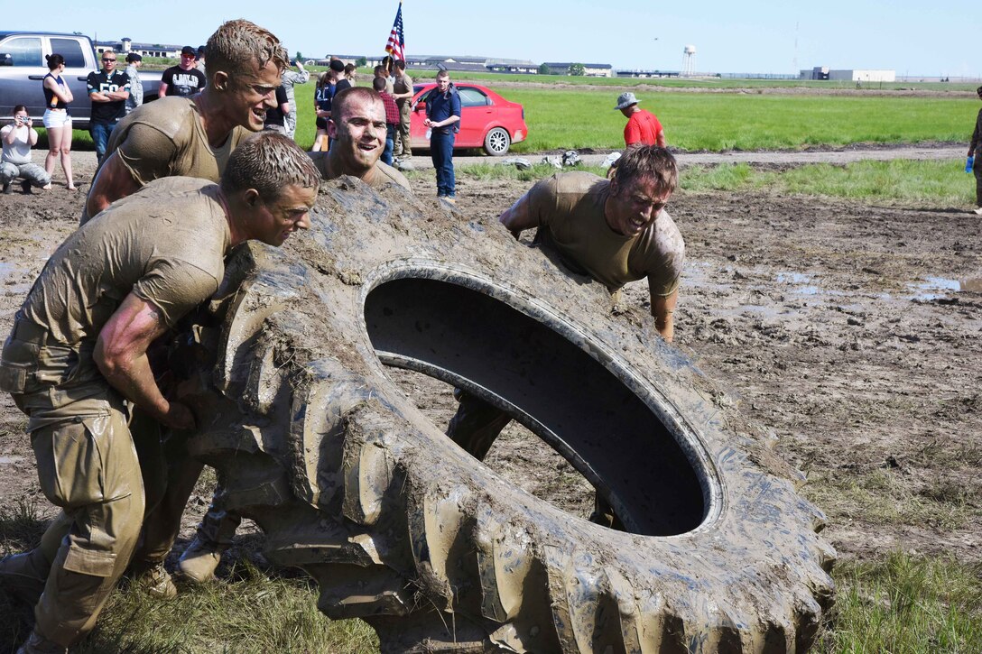 Team Malmstrom members from the 341st Security Forces Group work in unison to flip a tire during the 4th Annual Aces Cop Combat Challenge at Malmstrom Air Force Base Mont., June 5. In total, 22 stations made up the event for security forces members to complete before judges determined the winning team. (U.S. Air Force photo/Airman 1st Class Collin Schmidt)