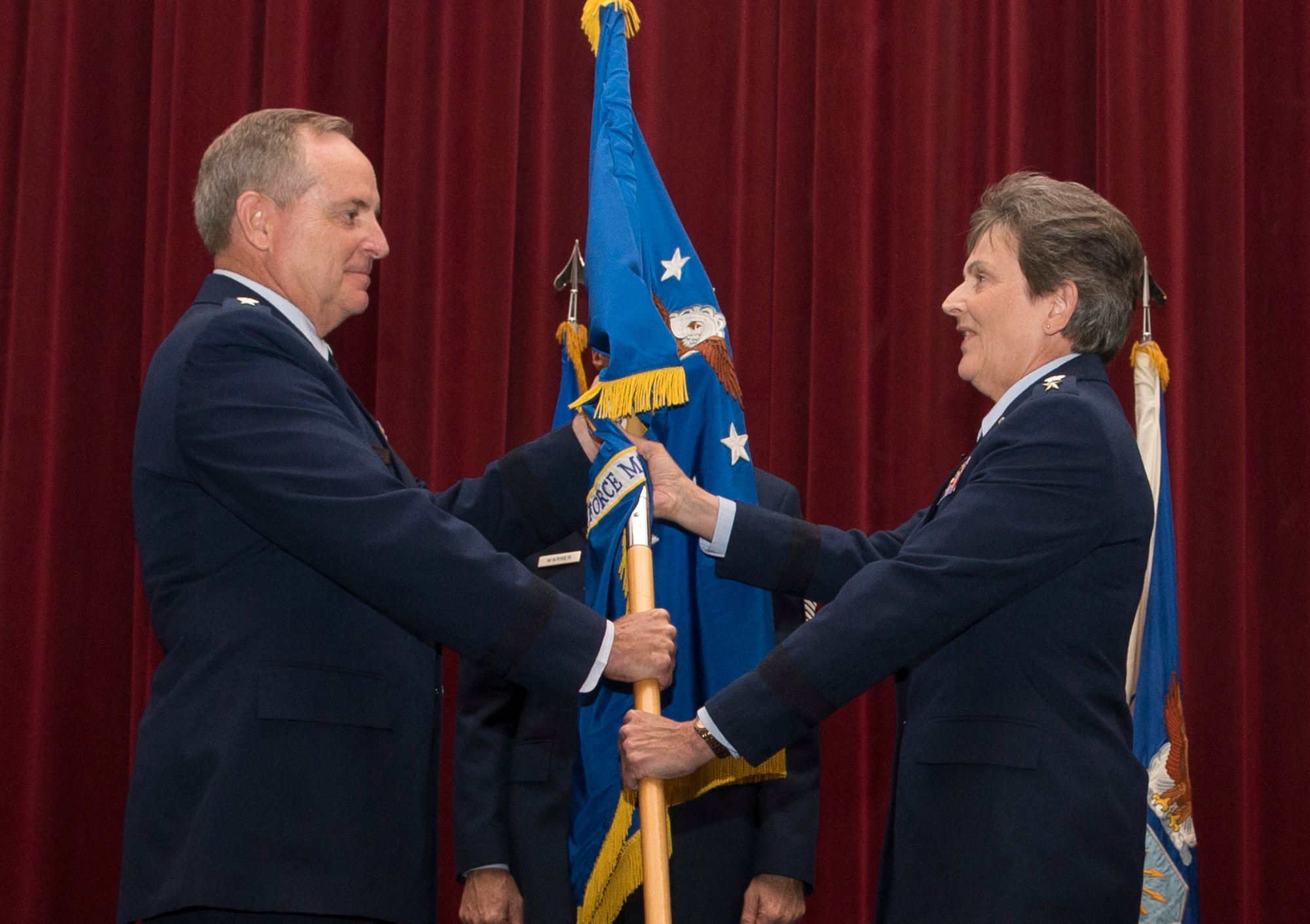 In the time-honored military tradition signifying assumption of command, Air Force Chief of Staff Gen. Mark. A. Welsh III passes the Air Force Materiel Command guidon, or unit flag, to Gen. Ellen Pawlikowski. Pawlikowski assumed command of AFMC Jun. 8, 2015, in a ceremony at the Air Force Institute of Technology's Kenney Auditorium. (U.S. Air Force photo/Wes Farnsworth)