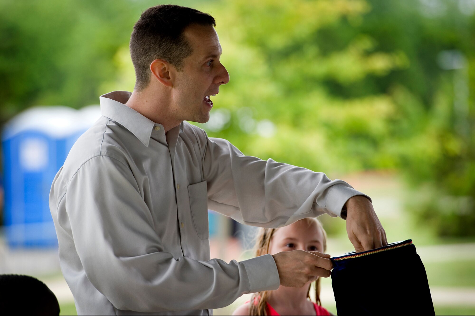 Alexis Ledbetter, daughter of Stephany Smith, watches as Master Sgt. Michael Darnell, 434th Logistics Readiness Squadron supply management craftsman, performs a magic trick at Grissom Air Reserve Base, Ind., June 6, 2015. Families had an opportunity to learn about the base, its mission as well as participate in some morale building fun. (U.S. Air Force photo/Tech. Sgt. Douglas Hays)