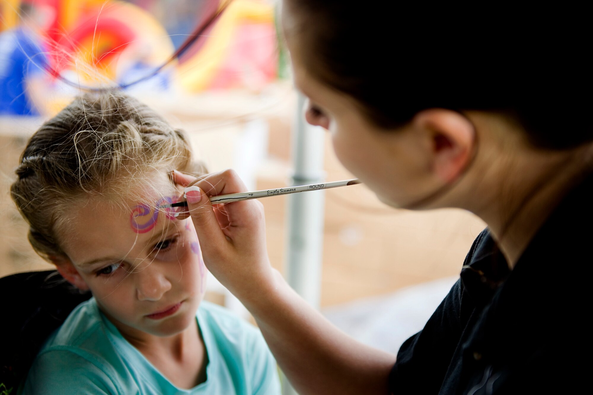 Grace Fackler, daughter of Mark Fackler, 434th Civil Engineer Squadron deputy fire chief, holds still while Valleri Bowman, a contracted artist, during the family day picnic at Grissom Air Reserve Base, Ind., June 6, 2015. Family members had a chance to see what their loved ones do at Grissom and to enjoy an afternoon of fun and festivities. (U.S. Air Force photo/Tech. Sgt. Douglas Hays)