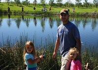 Jaycee, 5, left, Harper, 3, right and Staff Sgt. Colton Chandler, center, 12th Missile Squadron facility manager participates in National Fishing and Boating Week, Jun. 6, 2015, at Pow Wow Park, Malmstrom Air Force Base, Mont. Each person was allowed to catch two fish and have the fish weighed.  (U.S. Air Force photo/2nd Lt. Annabel Monroe)