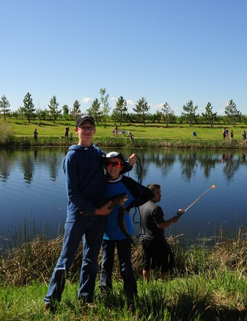 Briton Bare, 17, left and Brant Bare, 12, right, sons of Britt Bare, a Kids Fishing Day volunteer from the 341st Civil Engineering Squadron, proudly display their catches during Kids Fishing Day, Jun. 6, 2015, at Pow Wow Park, Malmstrom Air Force Base, Mont. National Fishing and Boating Week is the week of June 6-14, 2015. (U.S. Air Force photo/2nd Lt. Annabel Monroe)