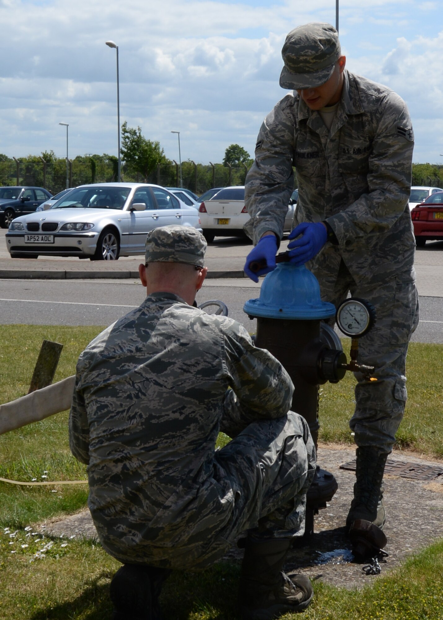 U.S. Air Force Senior Airman Joshua Slater, left, from Springfield, Mo., prepares to check the static water pressure on a fire hydrant which is linked to the base water mains while U.S. Air Force Airman 1st Class Jarrad Faulkner, right, from Hamilton, Ohio, both 100th Civil Engineer Squadron water and fuels system maintenance journeymen, taps into the base water supply June 3, 2015, on RAF Mildenhall, England. Once the hydrant had been tapped into they measured the static water pressure, and confirmed the base water pressure is at least 52 pounds per square inch. (U.S. Air Force photo by Gina Randall/Released)