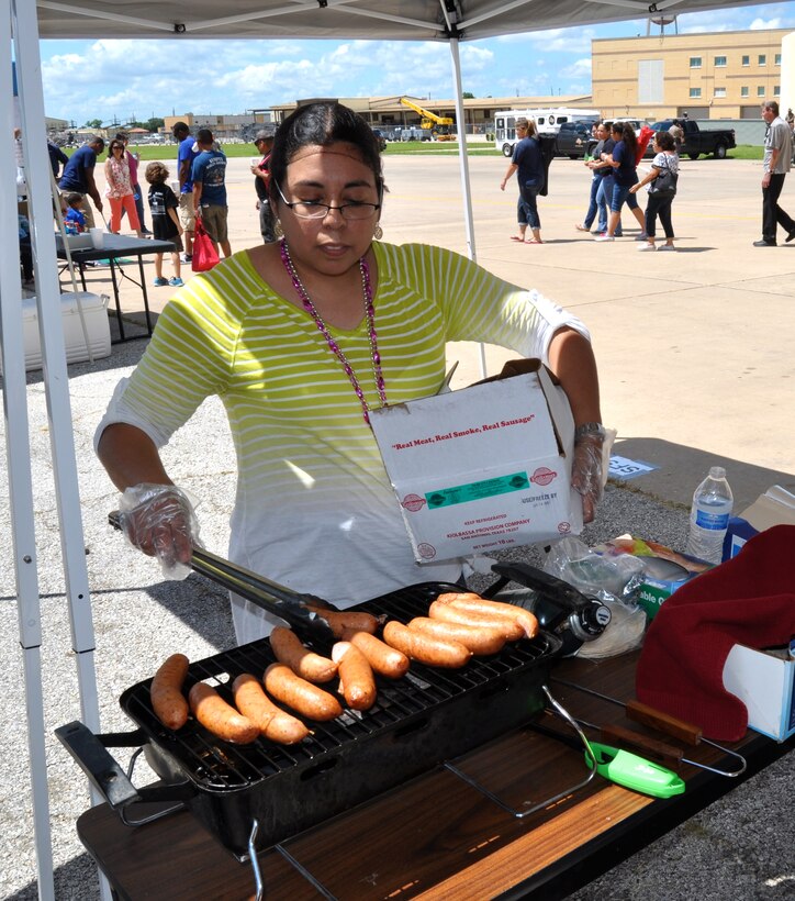 Tech Sgt. Herlinda Trevino, 433rd Medical Squadron Health Services manager, throws a few more kielbasas on the grill to help raise funds for her squadron during the 433rd Airlift Wing's Family Day, June 7, 2015 at Joint Base San Antonio-Lackland Texas. The food was a big attraction for Family Day as families were served pizza, hamburgers, nachos and hotdogs. (U.S. Air Force photo/Senior Airmen Bryan Swink)
