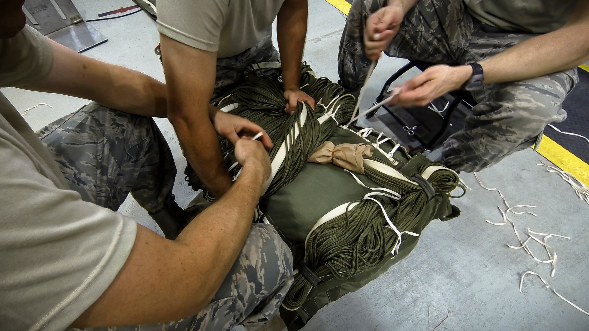 Technical Sgt. Jesse Sorrell (left), Technical Sgt. Jeremy Martinson and Technical Sgt. Joshua Ellis ties up a G-12E Type V platform parachute after recovering it from the dropzone on June 6, 2015. The Airman from the 182d Airlift Wing, Small Air Terminal, Peoria, Ill. check and repack the parachute after it was used in a recent C-130 air drop training mission with heavy equipment at the dropzone. (U.S. Air National Guard photo by Master Sgt. Scott Thompson/Released)
