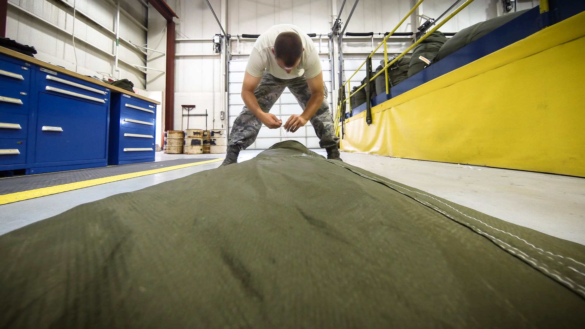 Technical Sgt. Jeremy Martinson ties up a G-12E Type V platform parachute after recovering it from the dropzone on June 6, 2015. The Airman from the 182d Airlift Wing, Small Air Terminal, Peoria, Ill. check and repack the parachute after it was used in a recent C-130 air drop training mission with heavy equipment at the dropzone. (U.S. Air National Guard photo by Master Sgt. Scott Thompson/Released)