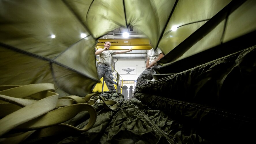 Technical Sgt. Jesse Sorrell (left) and Technical Sgt. Jeremy Martinson untagle parachute cord on a G-12E Type V platform parachute after recovering it from the dropzone on June 6, 2015. The Airman from the 182d Airlift Wing, Small Air Terminal, Peoria, Ill. check and repack the parachute after it was used in a recent C-130 air drop training mission with heavy equipment at the dropzone. (U.S. Air National Guard photo by Master Sgt. Scott Thompson/Released)