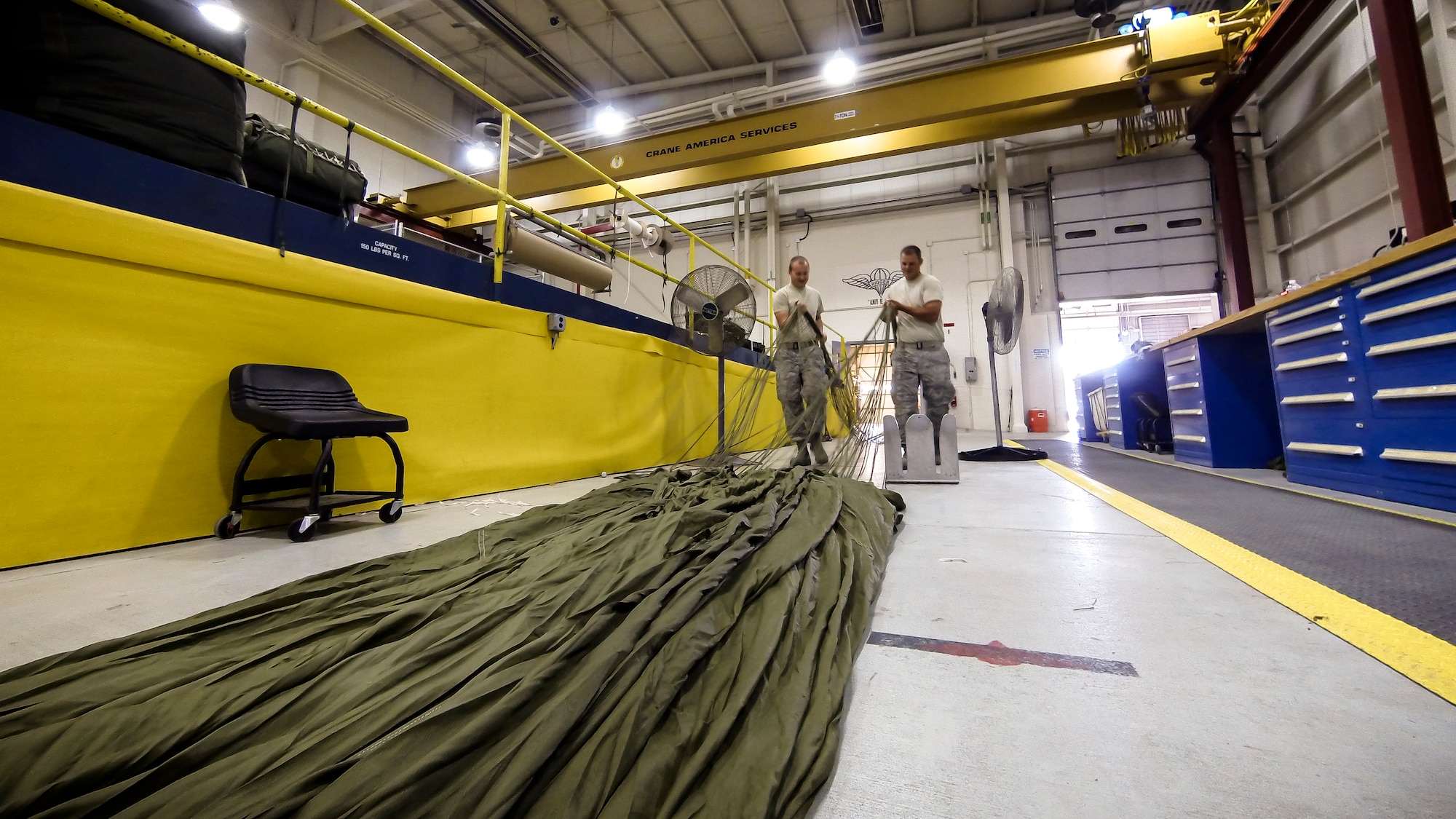 Technical Sgt. Jesse Sorrell (left) and Technical Sgt. Jeremy Martinson untagle parachute cord on a G-12E Type V platform parachute after recovering it from the dropzone on June 6, 2015. The Airman from the 182d Airlift Wing, Small Air Terminal, Peoria, Ill. check and repack the parachute after it was used in a recent C-130 air drop training mission with heavy equipment at the dropzone. (U.S. Air National Guard photo by Master Sgt. Scott Thompson/Released)
