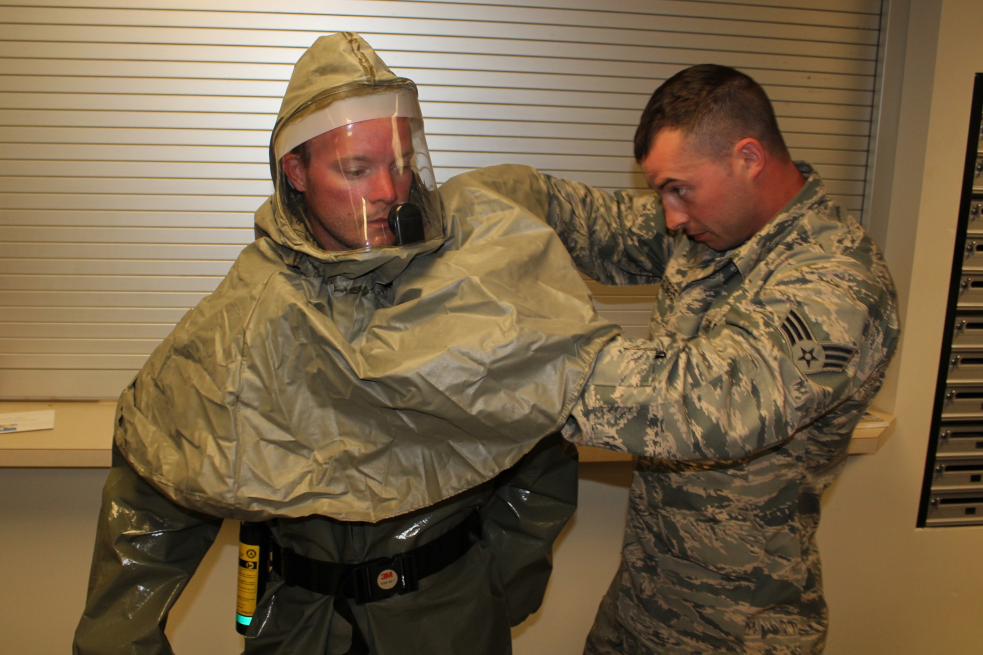 150605-Z-VA676-009 – Senior Airman Louis Boggs assists Staff Sgt. Justin Sawgle as he dons a protective suit that would allow him to work in a hazardous environment. Boggs is a member of the 191st Aircraft Maintenance Squadron and Sawgle is a member of the 127th Logistics Readiness Squadron. Both Airmen are augmentees to the 127th Medical Group for response to a hazardous material situation. During a June 5, 2015, training exercise at Selfridge Air National Guard Base, Mich., the Airmen reviewed the use of the protective suits and related equipment. Airmen at Selfridge conduct a variety of training exercises every year to be able to respond to local emergencies and/or to deploy to forward locations. (U.S. Air National Guard photo by Tech. Sgt. Dan Heaton)