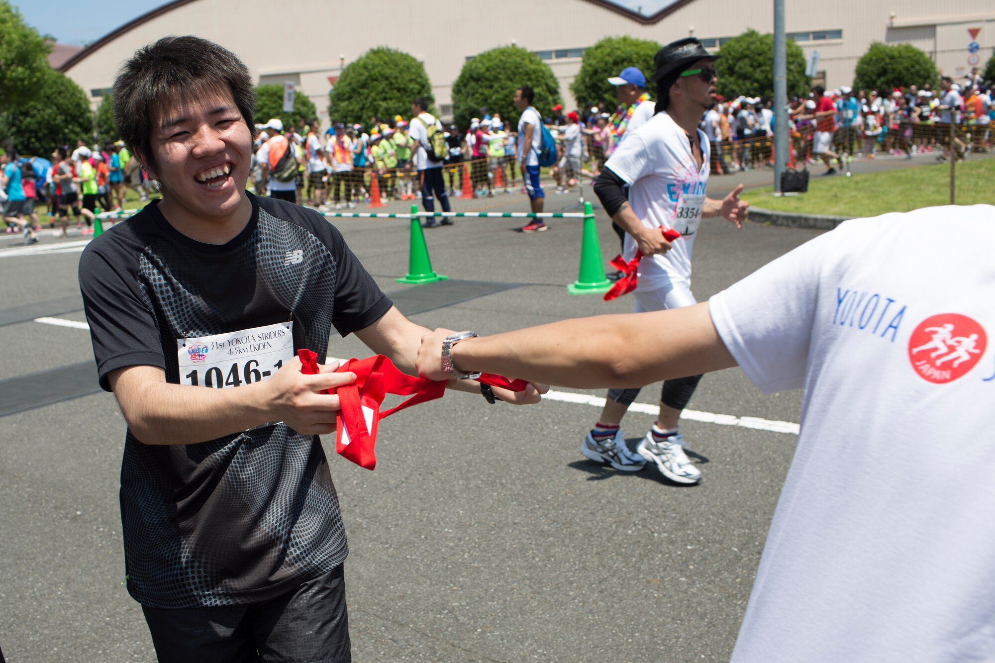 An Ekiden runner hands off a tasuki, a cloth sash, to the next runner during the 31st Annual Ekiden race at Yokota Air Base, Japan. More than 5,800 runners participated in the event sponsored by the Yokota Striders Running Club. (U.S. Air Force photo by Osakabe Yasuo/Released) 