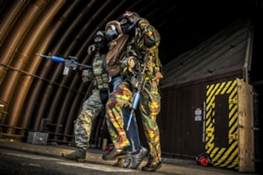 A U.S. airman, left, and a European security force member carry a simulated wounded enemy out of a facility during a combat training course on Ramstein Air Base, Germany, May 30, 2015.