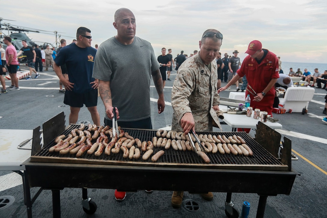 The Marines and Sailors of the 15th Marine Expeditionary Unit and USS Anchorage (LPD 23) cook hot dogs to be served at a steel beach picnic aboard the USS Anchorage in the Philippine Sea, June 4, 2015. The Marines and Sailors of the 15th MEU and Essex Amphibious Ready Group hold such events to boost morale and build camaraderie. (U.S. Marine Corps photo by Sgt. Steve H. Lopez/Released)