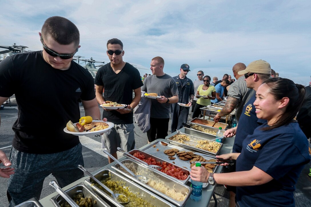 The Marines and Sailors of the 15th Marine Expeditionary Unit and USS Anchorage (LPD 23) serve food to the Marines and Sailors at a steel beach picnic aboard the USS Anchorage in the Philippine Sea, June 4, 2015. The Marines and Sailors of the 15th MEU and Essex Amphibious Ready Group hold such events to boost morale and build camaraderie. (U.S. Marine Corps photo by Sgt. Steve H. Lopez/Released)
