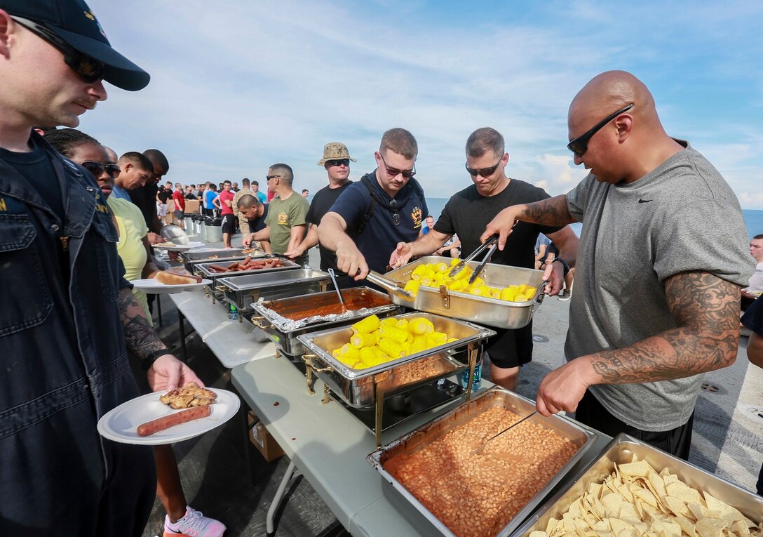 The Marines and Sailors of the 15th Marine Expeditionary Unit and USS Anchorage (LPD 23) serve food to the Marines and Sailors at a steel beach picnic aboard the USS Anchorage in the Philippine Sea, June 4, 2015. The Marines and Sailors of the 15th MEU and Essex Amphibious Ready Group hold such events to boost morale and build camaraderie. (U.S. Marine Corps photo by Sgt. Steve H. Lopez/Released)
