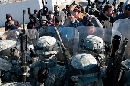 New Mexico Army National Guard Soldiers from C Company, 1st Battalion, 200th Infantry Regiment, confront a riot during a demonstration of their capabilities at Camp Atterbury Joint Maneuver Training Center, Ind. Feb. 10, 2011. C Company is part of a task force deploying to Kosovo, a former Yugoslav republic that is now a sovereign state, to aid in stability efforts.