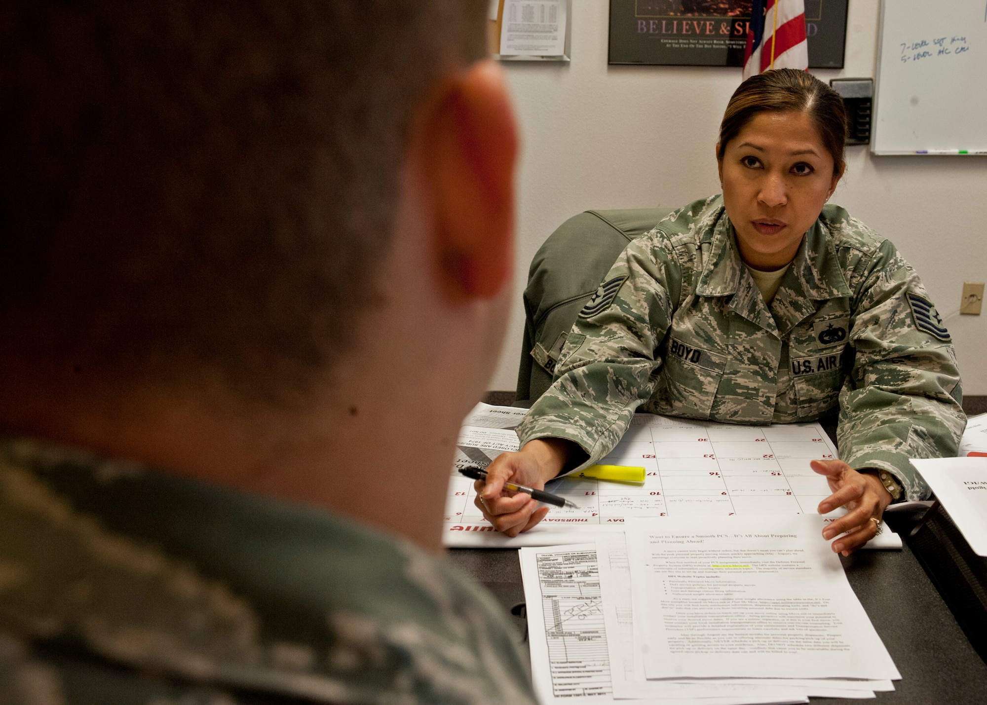 Tech. Sgt. Aileen Boyd, 99th Logistics Readiness Squadron NCO in charge of household goods and passenger travel, provides an Airman information for their permanent change of station at Nellis Air Force Base, Nev., June 3, 2015. Included on the sheet is information regarding move.mil, where Airmen will find all the information needed to accomplish a successful PCS. (U.S. Air Force photo by Airman 1st Class Jake Carter)