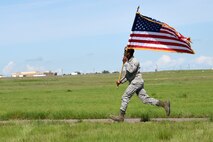 A Team Malmstrom member runs while holding the American flag at the Annual Aces Cop Combat Challenge June 5, 2015, at Malmstrom Air Force Base, Mont. This was the fourth annual challenge put on by security forces to encourage Airmen to push their body and mind outside of a normal routine. (U.S. Air Force photo/Chris Willis)