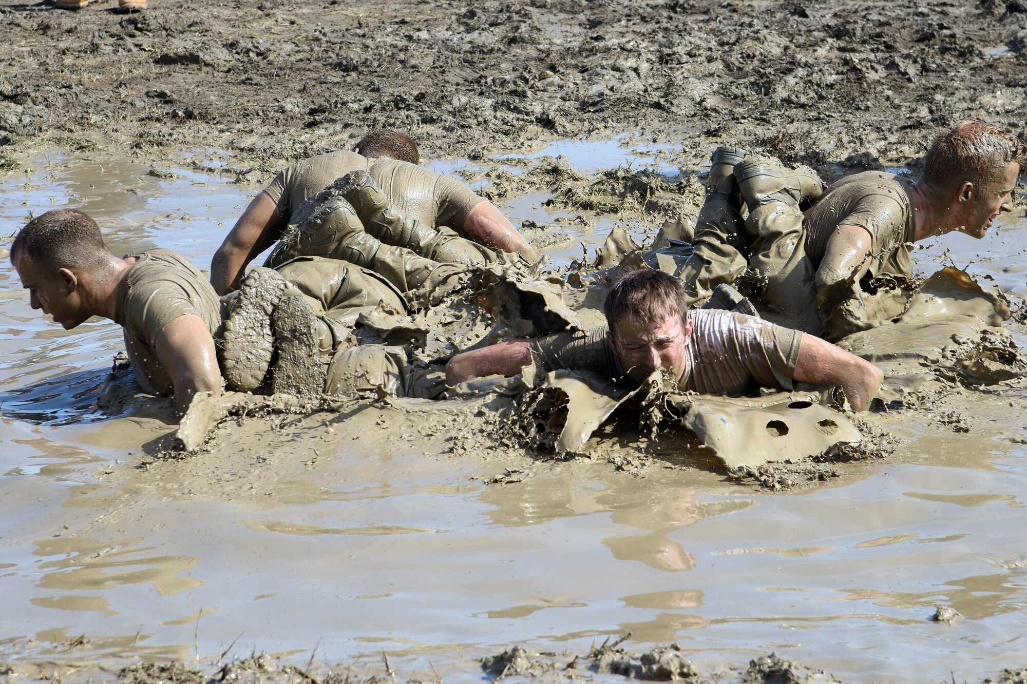 Team Malmstrom members from the 341st Security Forces Group work through sweat and mud while trying to accomplish multiple sets of team pushups in shallow water June 5, 2015, at Malmstrom Air Force Base, Mont. In total, 22 stations and events meant for security forces members to complete before judges determined the winning team. (U.S. Air Force photo/Chris Willis)
