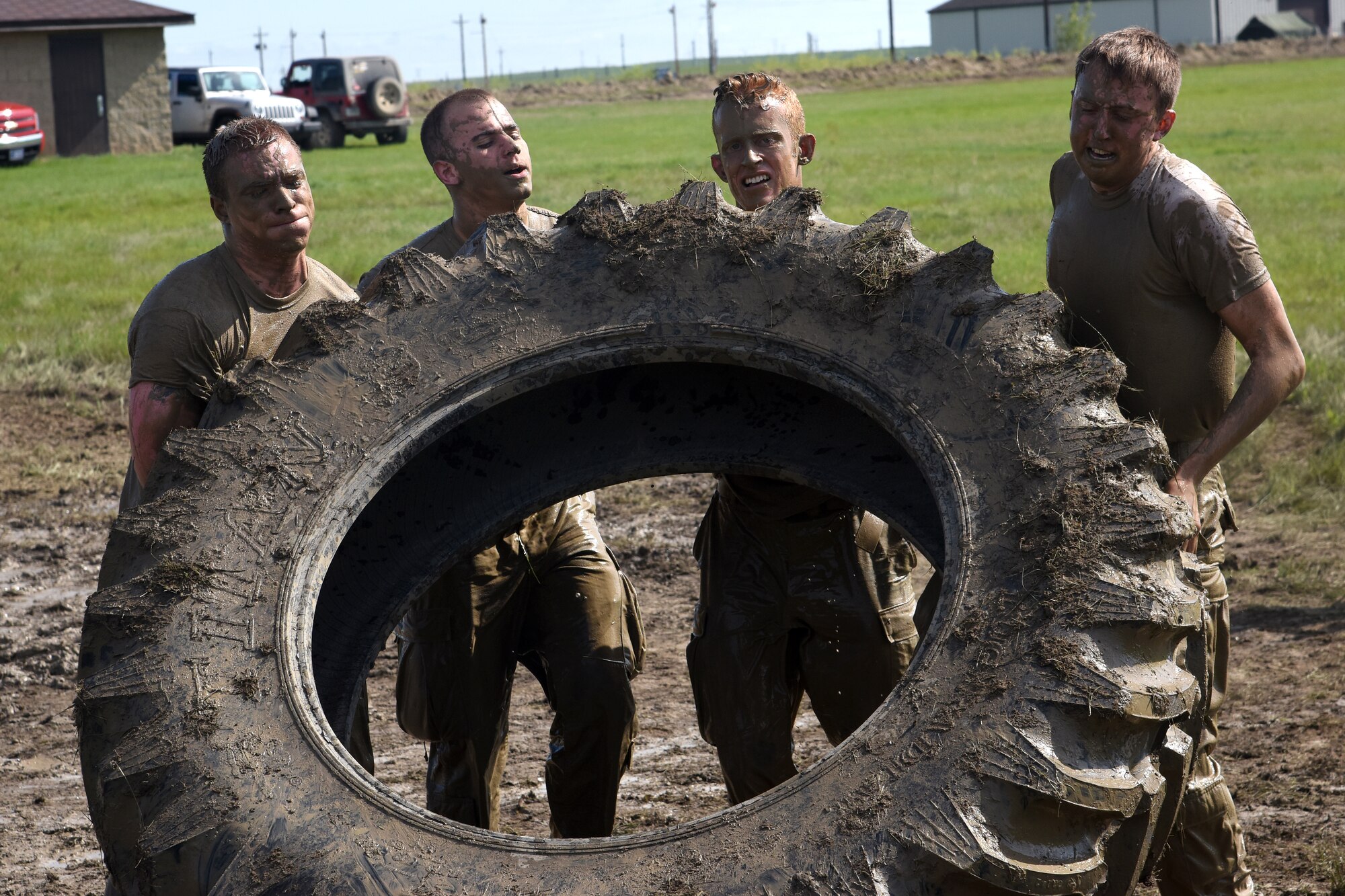 Team Malmstrom members from the 341st Security Forces Group work through sweat and mud while trying to move an oversize tire multiple times across a field June 5, 2015, at Malmstrom Air Force Base, Mont. Security Forces members had to complete 22 different challenging stations.  (U.S. Air Force photo/Chris Willis)