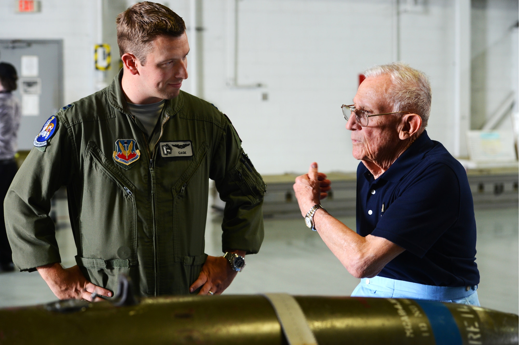 A retired U.S. Air Force Wild Weasel speaks to a current Wild Weasel fighter pilot at Shaw Air Force Base, S.C., June 5, 2015. The Wild Weasels toured the 20th Maintenance Group’s weapons standardization and evaluation hangar to learn about the munitions the 20th Fighter Wing employs in combat. (U.S. Air Force photo by Senior Airman Jonathan Bass/Released)