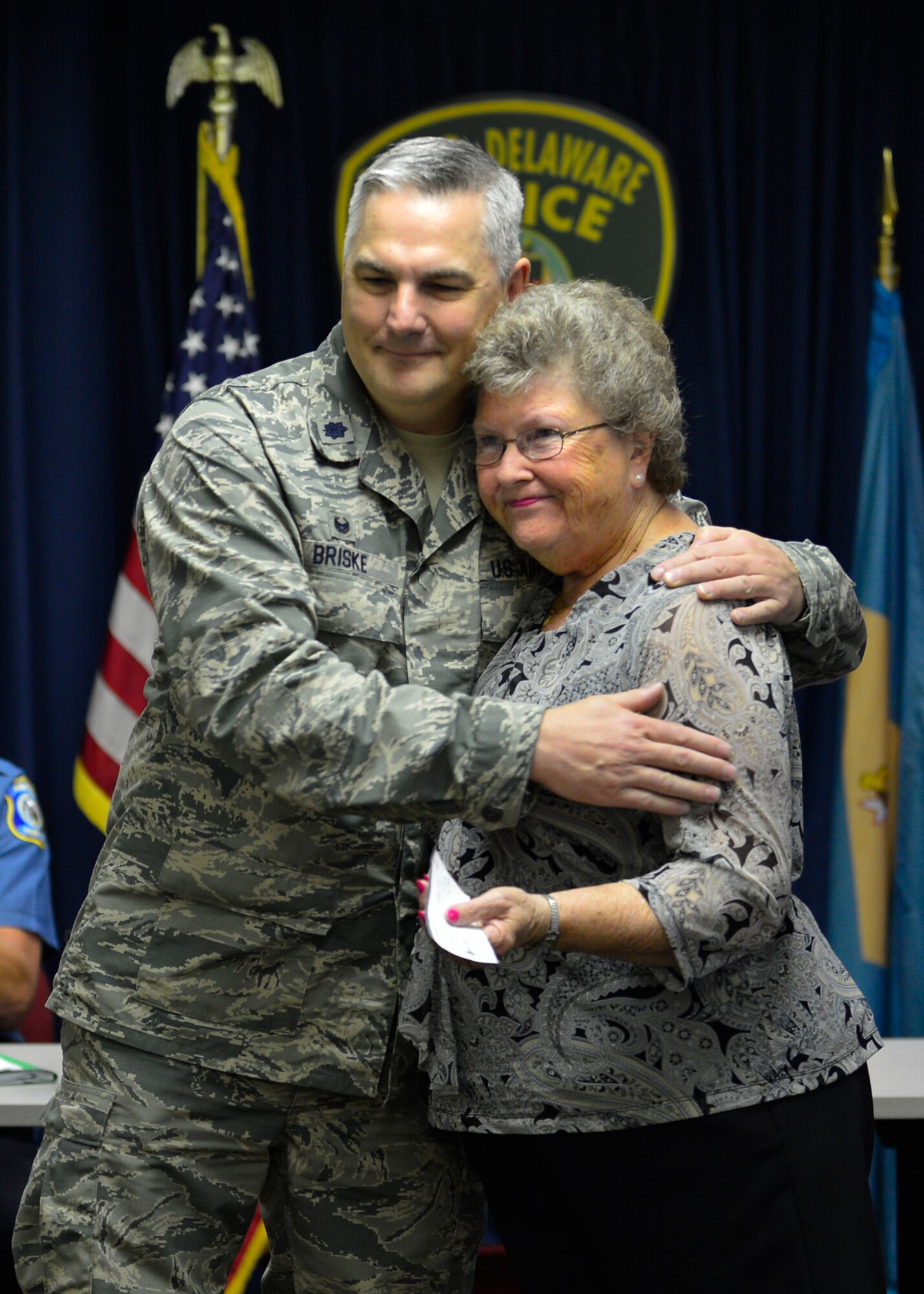 Eleanor Allione, Concerns of Police Survivors Delaware Chapter president, hugs Lt. Col. Joel Briske, then 436th Security Forces Squadron commander, after she received an $8,000 check for the C.O.P.S. organization June 9, 2015, at the Dover Police Department in Dover, Del. C.O.P.S. was established in 1984 and provides resources to families and co-workers of law enforcement officers who have died in the line of duty. (U.S. Air Force photo/Airman 1st Class William Johnson)
