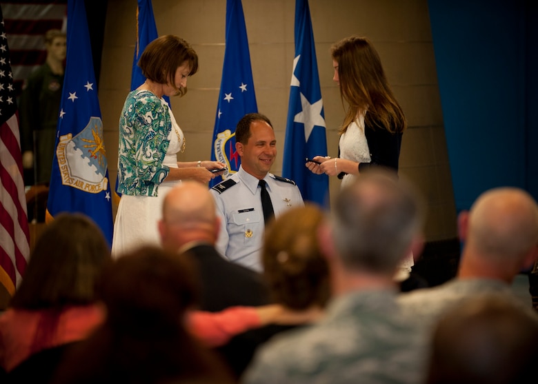 PETERSON AIR FORCE BASE, Colo. – Brig. Gen. John Shaw, 21st Space Wing commander, kneels as his wife and daughter put the first set of stars on his shoulders at his promotion ceremony at the Peterson Air and Space Museum, June 5, 2015. Shaw took command of the 21st Space Wing July 26, 2013 and will move on to Offutt Air Force Base, Neb., June 12 as deputy director for U.S. Strategic Command. (U.S. Air Force photo by Airman 1st Class Rose Gudex)