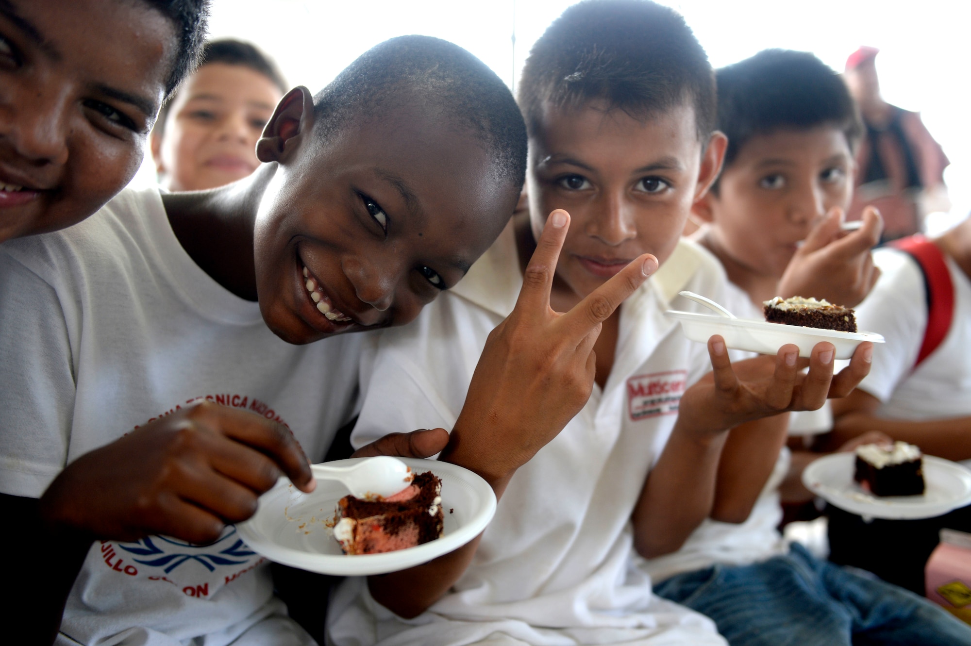 Children attending the Guardian of the Fatherland event at Puerto Castillo Naval Base in Trujillo, Honduras, June 6, 2015, eat dessert. The Guardians event is a twice annual event held at the base to reach at risk youth and provide them with instruction and training on human rights, military and spiritual training and English. NEW HORIZONS was launched in the 1980s and is an annual joint humanitarian assistance exercise that U.S. Southern Command conducts with a partner nation in Central America, South America or the Caribbean. The exercise improves joint training readiness of U.S. and partner nation civil engineers, medical professionals and support personnel through humanitarian assistance activities. (U.S. Air Force photo by Capt. David J. Murphy/Released)