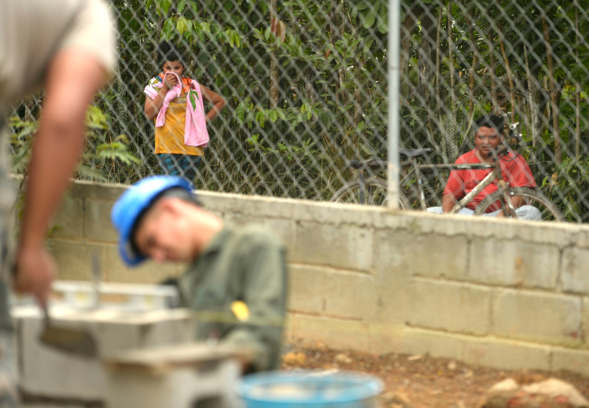 Honduran locals watch construction by U.S. Air Force Airmen from the 823rd Expeditionary RED HORSE Squadron, out of Hurlburt Field, Fla., and U.S. Marines from the 271st Marine Wing Support Squadron, 2nd Marine Air Wing, out of Marine Corps Air Station Cherry Point, N.C., as they work at the Gabriela Mistral school in Ocotes Alto, Honduras, June 3, 2015. The Airmen and Marines work together as part of the New Horizons Honduras 2015 training exercise, an annual humanitarian exercise put on by U.S. Southern Command. New Horizons was launched in the 1980s and is an annual joint humanitarian assistance exercise that U.S. Southern Command conducts with a partner nation in Central America, South America or the Caribbean. The exercise improves joint training readiness of U.S. and partner nation civil engineers, medical professionals and support personnel through humanitarian assistance activities. (U.S. Air Force photo by Capt. David J. Murphy/Released)