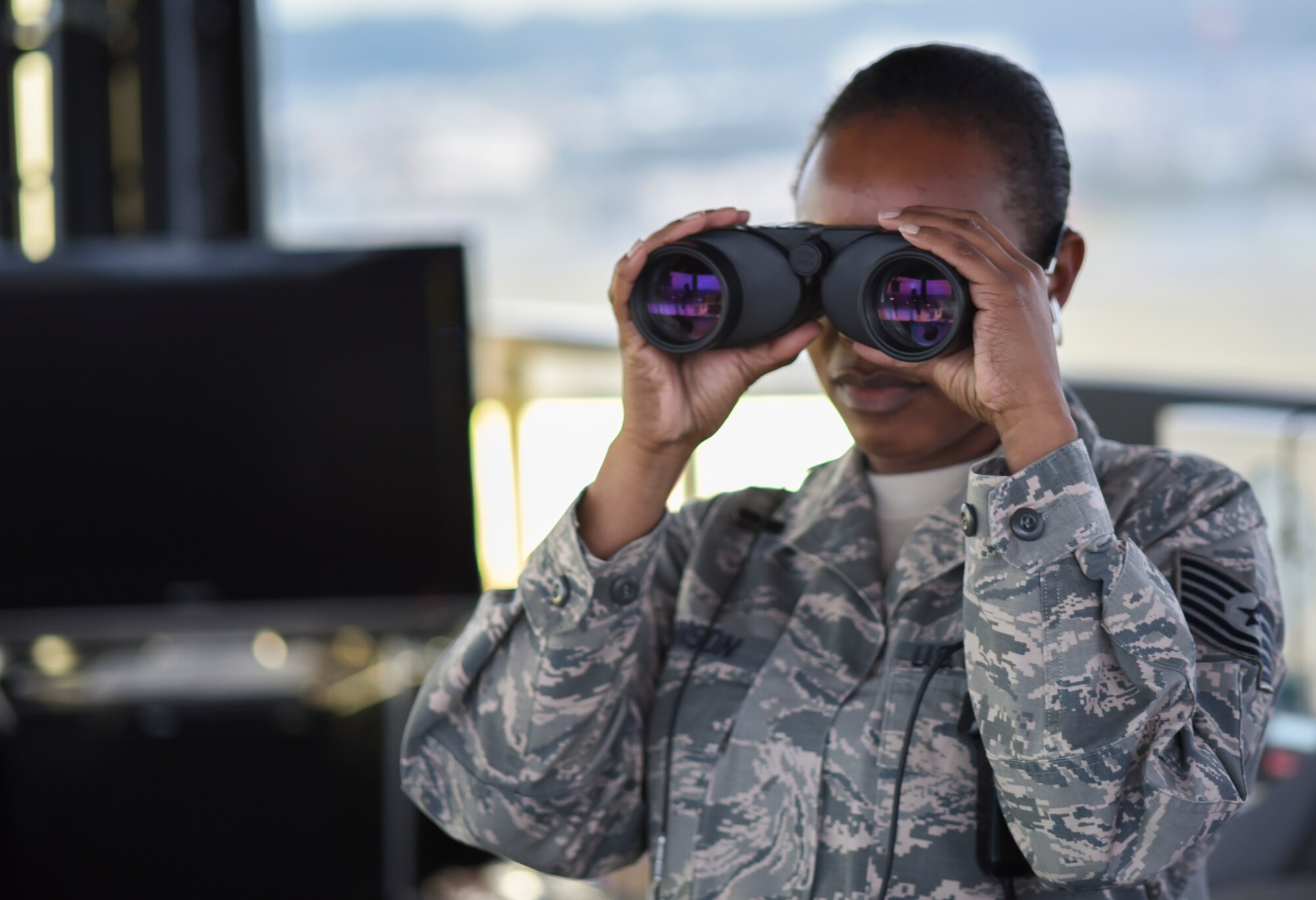 Tech. Sgt. Charmaine Johnson, 374th Operations Support Squadron tower watch supervisor, uses a pair of binoculars to monitor flightline activity from the air traffic control tower at Yokota Air Base, Japan, May 8, 2015. In addition to communicating with aircraft, controllers operate the lights for the flightline and overruns. (U.S. Air Force photo by Senior Airman Michael Washburn/Released)