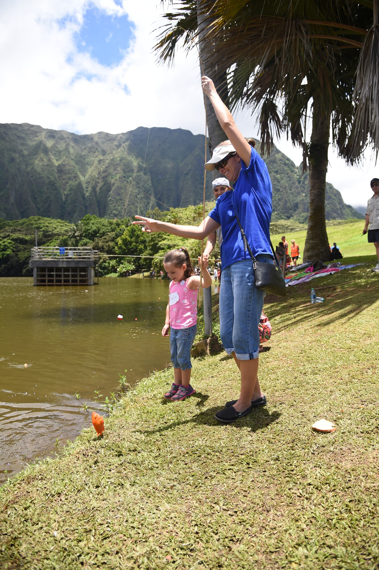 Tech. Sgt. Melissa Paul, 15th Wing command chief executive assistant, and her daughter Kaitlyn catch their first fish of the day at the 16th Annual Friends of Hickam Keiki Fishing Tournament at the Ho`omaluhia Botanical Gardens in Kaneohe, June 5, 2015. Every child walked away from the tournament with a new fishing pole and a fishing story. (U.S. Air Force photo by Tech. Sgt. Aaron Oelrich/Released)