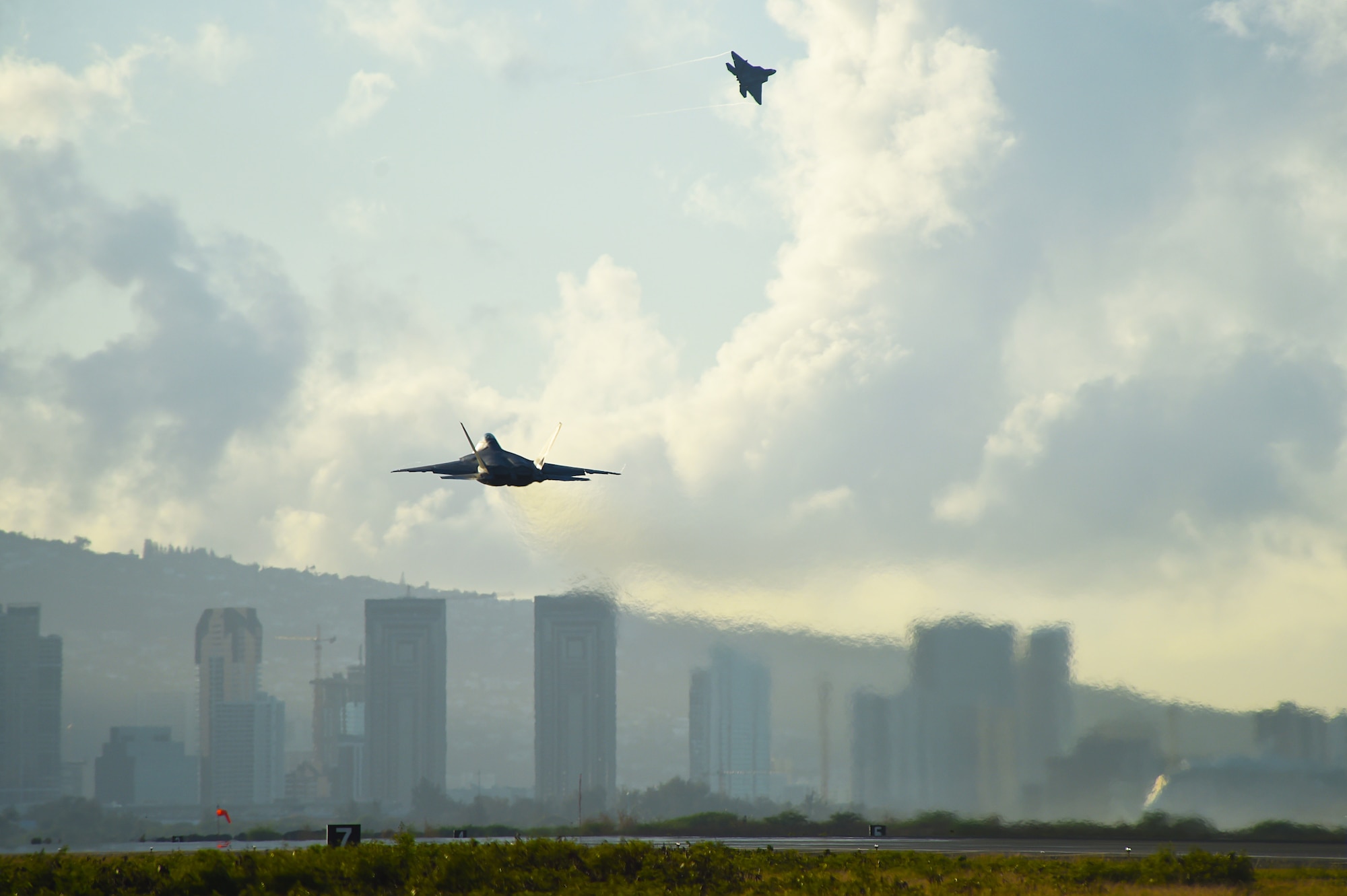 Two F-22 Raptors take off during a sortie surge from Joint Base Pearl Harbor-Hickam, Hawaii, June 6, 2015. Pilots of the F-22 from the Hawaii Air National Guard’s 199th Fighter Squadron and the 19th Fighter Squadron teamed up with maintenance Airmen from the 154th Wing and 15th Maintenance Group to launch and recover 62 Raptors in a day. The increase in sorties tested the flying capability of the total force integration squadron known as the Hawaiian Raptors. (U.S. Air Force photo by Tech. Sgt. Aaron Oelrich/Released)   