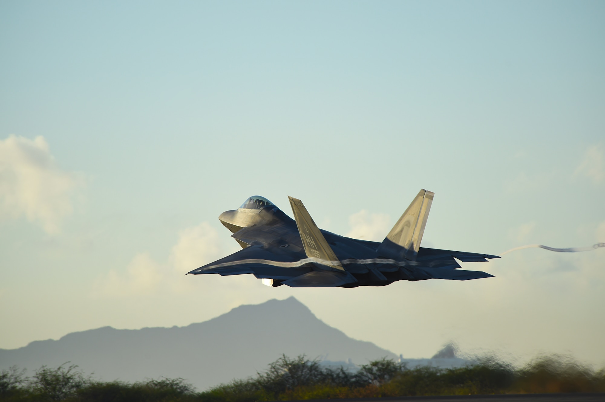 A F-22 Raptor, from the 199th Fighter Squadron, increases altitude shortly after taking off from Joint Base Pearl Harbor-Hickam, Hawaii, June 6, 2015. Pilots of the F-22 from the Hawaii Air National Guard’s 199th Fighter Squadron and the 19th Fighter Squadron teamed up with maintenance Airmen from the 154th Wing and 15th Maintenance Group to launch and recover 62 Raptors in a day. The previous record was 46 sorties in one day with 14 aircraft, this recorded was broken using only 12 of the 18 aircraft in the smallest F-22 squadron in the Air Force. (U.S. Air Force photo by Tech. Sgt. Aaron Oelrich/Released)   