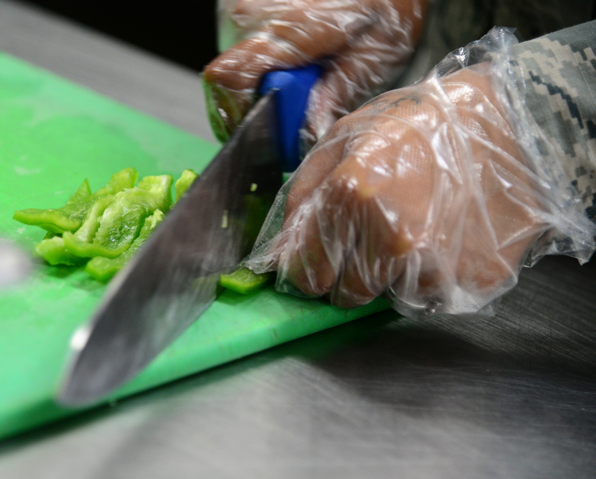 Airman 1st Class Linsun Jackson, 51st Force Support Squadron food service specialist, chops bell peppers April 2, 2015, at Osan Air Base, Republic of Korea. Food service specialists prepare food items for each meal two hours before hand. (U.S. Air Force photo by Senior Airman Matthew Lancaster)