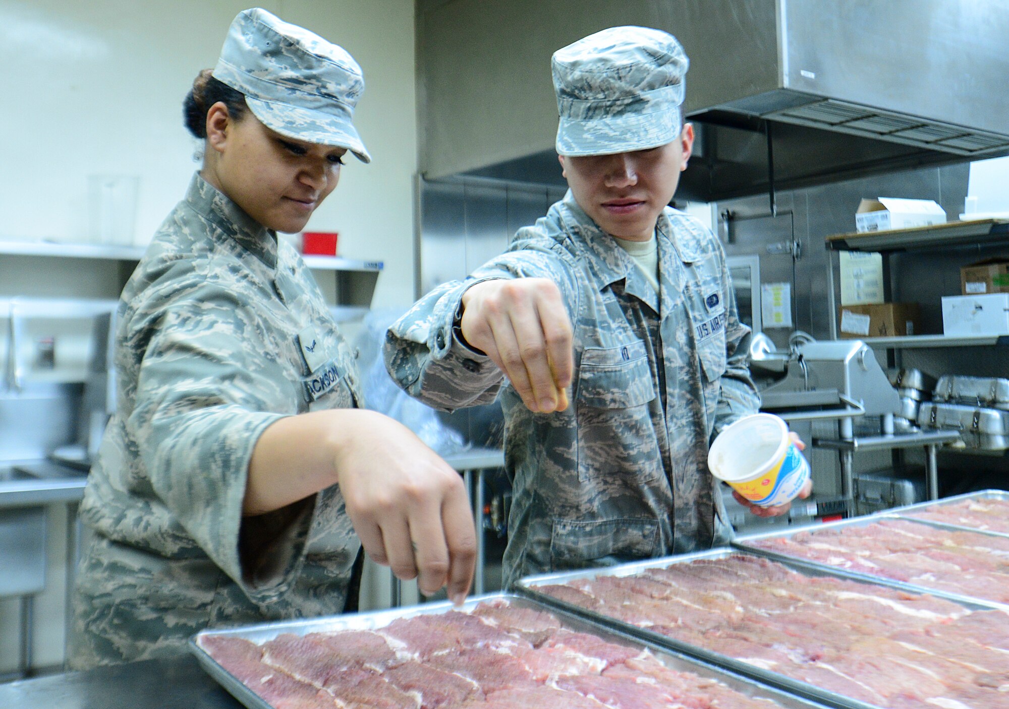 Airman 1st Class Linsun Jackson and Senior Airman Phulng Vo, 51st Force Support Squadron food service specialists, season pork chops April 1, 2015, at Osan Air Base, Republic of Korea. Shift workers prepare each meal in accordance with the menu set out by the Air Force Services Agency. (U.S. Air Force photo by Senior Airman Matthew Lancaster)