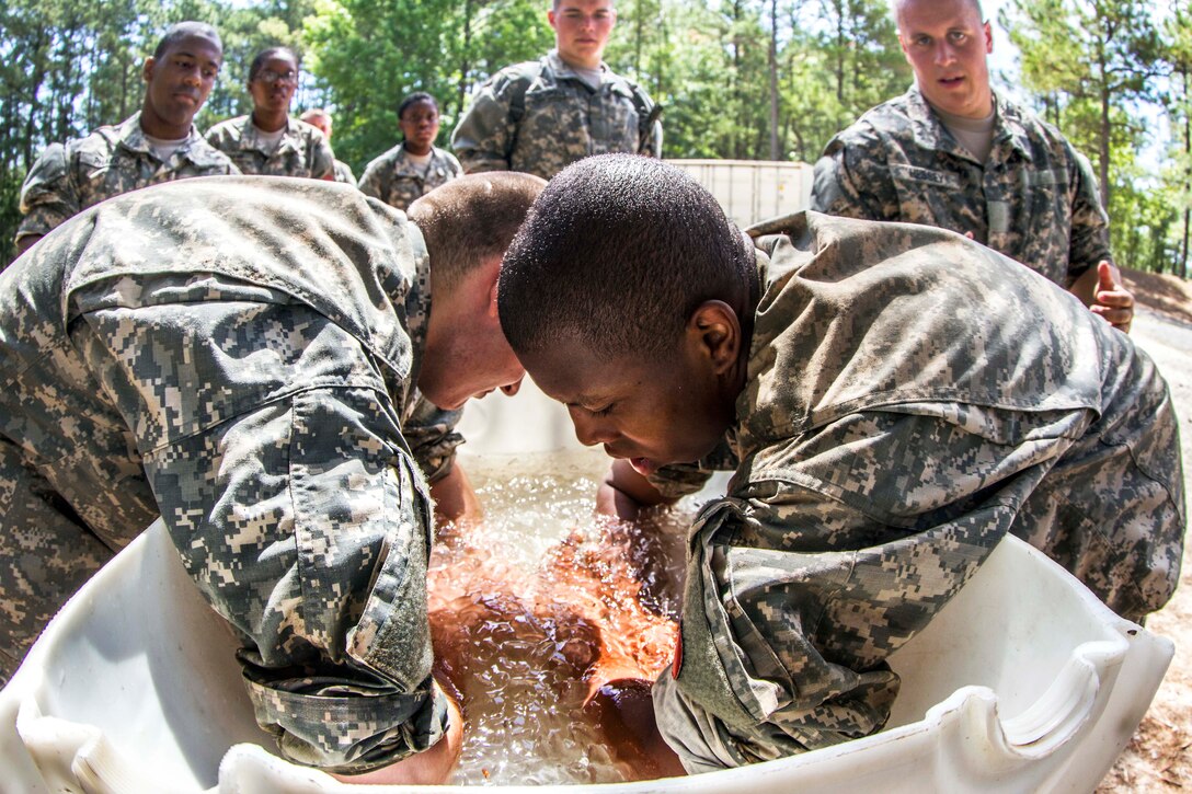Soldiers submerge their arms in ice water for a few seconds to cool down after completing the final hurdle of the endurance obstacle course during their second week of basic combat training at Fort Jackson, S.C., May 29, 2015.