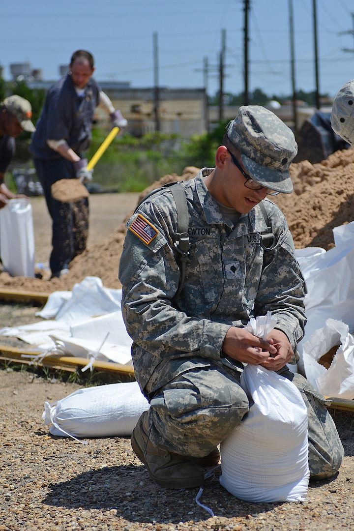 Spc. Nathan Newton, a food service specialist with the Louisiana National Guard’s Forward Support Company, 527th Engineer Battalion, closes a sandbag at Camp Minden in Minden, Louisiana, as part of preventative efforts for flooding from the Red River, June 6, 2015. 