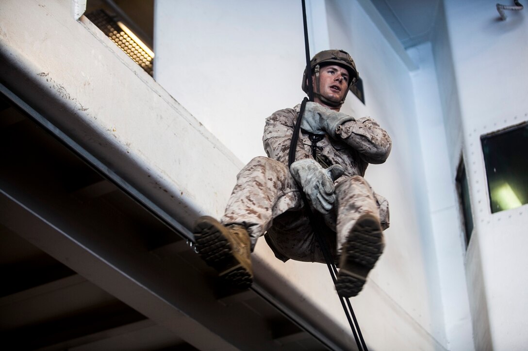 U.S. Marine Gunnery Sgt. Robert Turek demonstrates locking out while rappelling in the hangar bay of the USS Essex (LHD 2) in the East China Sea, June 2, 2015. Turek is with the 15th Marine Expeditionary Unit’s Maritime Raid Force. Locking out allows the Marines to stop descending in case they need to fix their gear or their landing area becomes unsafe. (U.S. Marine Corps photo by Cpl. Elize McKelvey/Released)