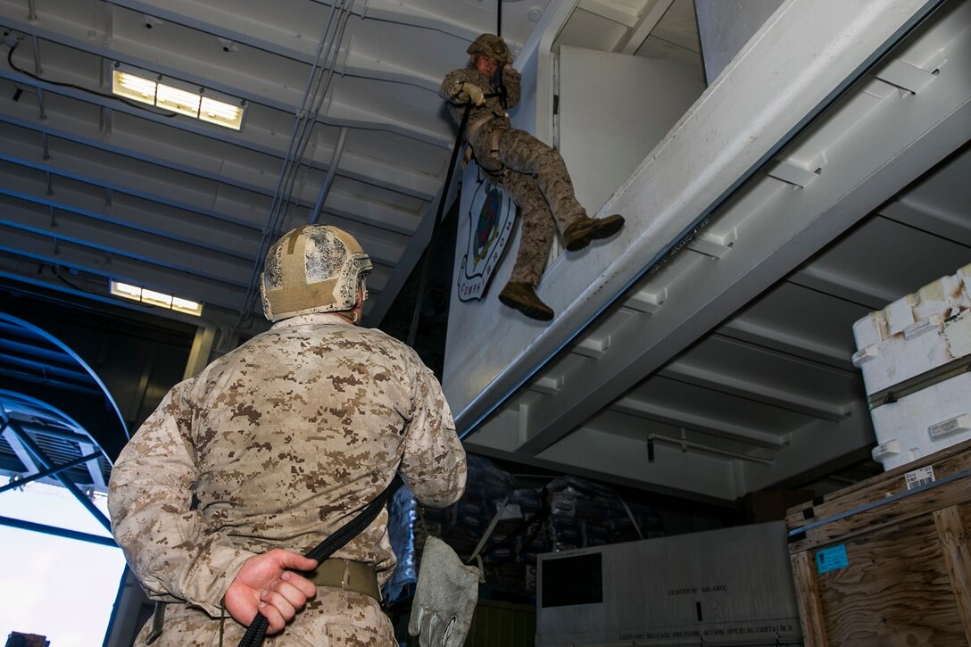 U.S. Marine Lance Cpl. Caleb Bray rappels in the hangar bay of the USS Essex (LHD 2) in the East China Sea, June 2, 2015. Bray is a member of the security element with the 15th Marine Expeditionary Unit’s Maritime Raid Force. Rappelling allows the Marines to lower themselves from any structure or vertical surface, allowing them to operate in any terrain. (U.S. Marine Corps photo by Cpl. Anna Albrecht/Released)