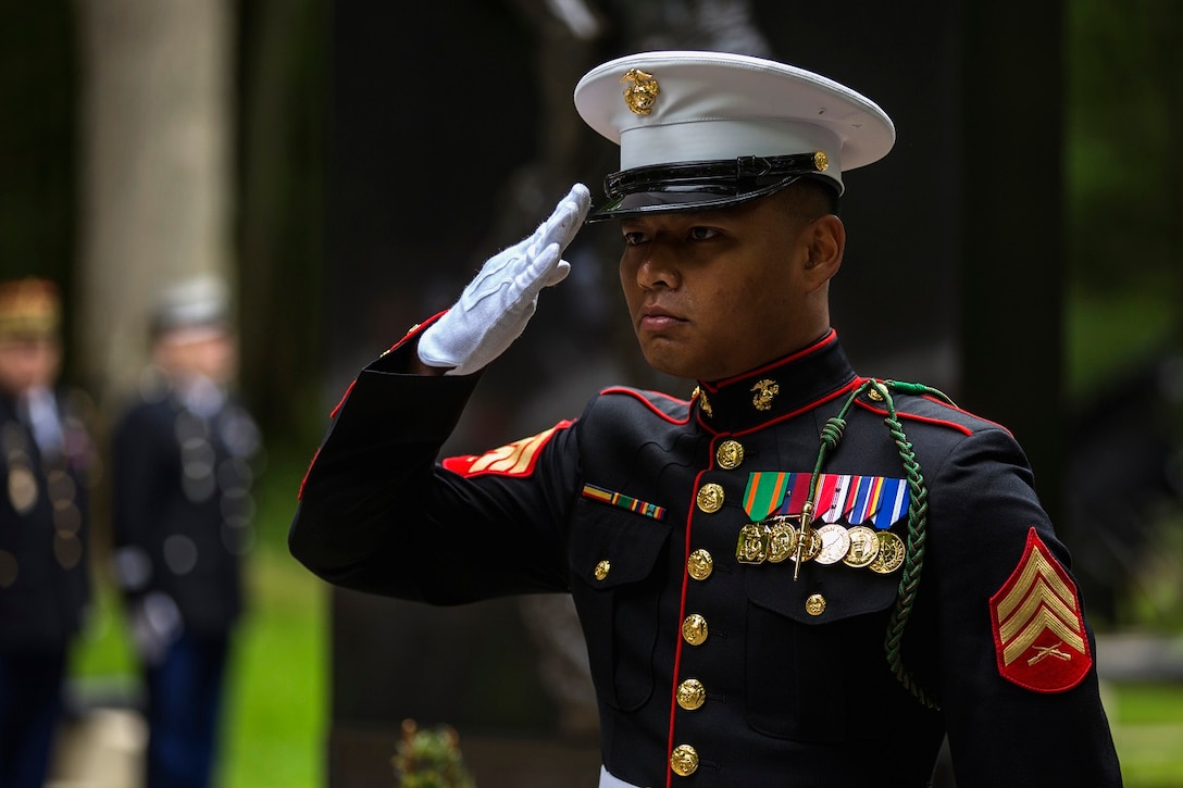 U.S. Marine Corps Sgt. Noukane Sonethanouvong, radio operator with communications company, headquarters battalion, 1st Marine Division  salutes while taps is played during a private ceremony at Aisne-Marne American Cemetery in Belleau, France on May 31, 2015. This Memorial Day ceremony was held in honor of the 97th anniversary of the Battle of Belleau Wood. (U.S. Marine Corps photo by Lance Cpl. Akeel Austin/Released)