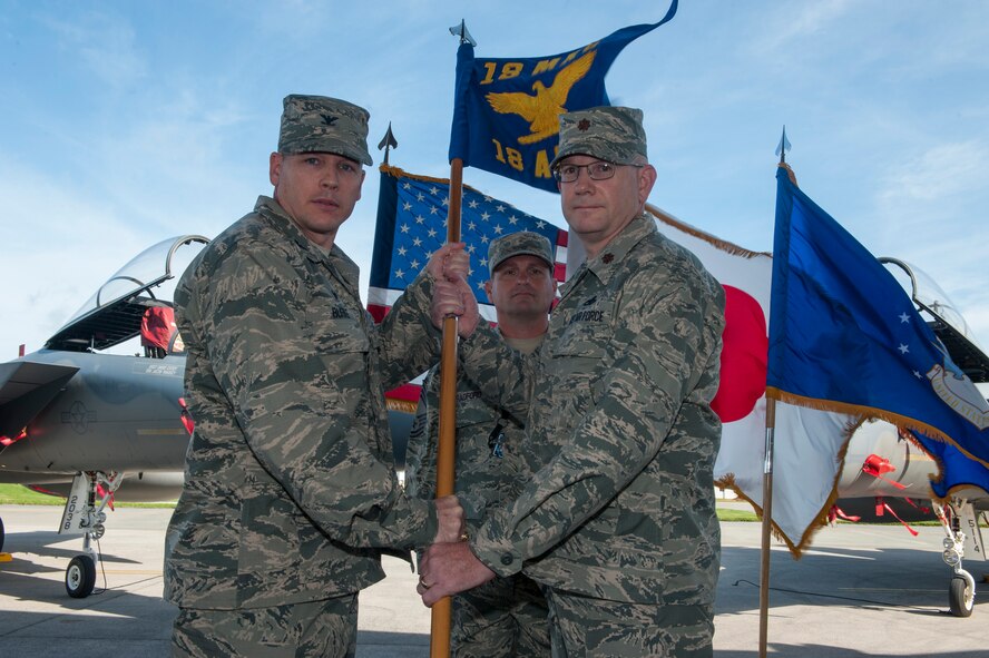 U.S. Air Force Col. Timothy Burke, 18th Maintenance Group commander, passes the guidon to Maj. Clarence McRae, 18th Aircraft Maintenance Squadron commander, as he accepts command of the squadron during a change of command ceremony on Kadena Air Base, Japan, June 11, 2015. McRae most recently served as the executive officer to deputy assistant secretary for programs, Office of the Assistant Secretary of the Air Force for Financial Management and Comptroller, Washington D.C. (U.S. Air Force photo by Senior Airman Stephen G. Eigel)