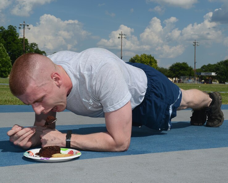 Airman 1st Class Curt Beach, 2nd Bomb Wing Public Affairs photojournalist, performs a plank while eating a piece of cake on Barksdale Air Force Base, La., June 9, 2015. While physical fitness is essential to maintaining a healthy lifestyle, bad nutrition can negate the positive effects of exercise. Incorporating fitness and good nutrition into one’s lifestyle will enhance quality of life. (U.S. Air Force photo/Senior Airman Benjamin Gonsier)