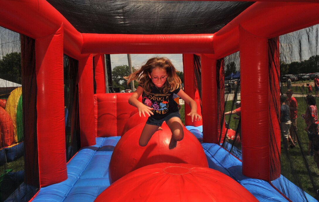 Nine-year-old Haylie Knight, daughter of U.S. Air Force Staff Sgt. Richard Knight, 55th Intelligence Support Squadron, makes her way down the Wiped Out inflatable attraction during the Offutt Appreciation Day Picnic June 5 at the Offutt Base Lake.  Several new inflatables made their debut this year, keeping kids entertained.  (U.S. Air Force photo by Josh Plueger/Released)